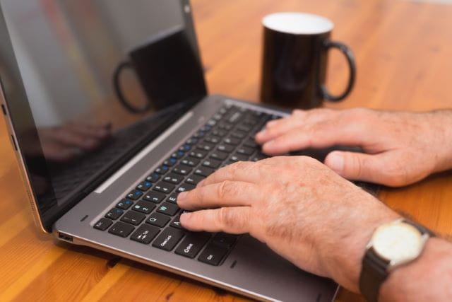 ældre mands hænder på tastatur