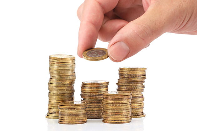 Hånd, der tager mønt fra stabler af mønter.